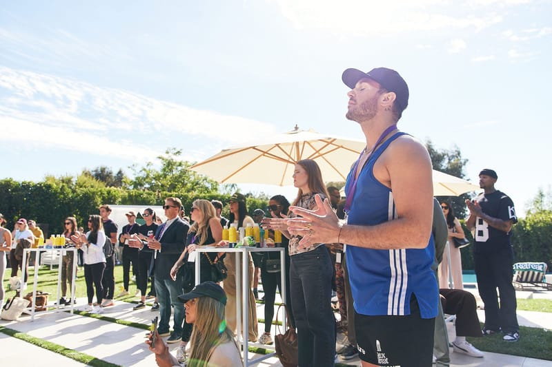 Guests standing on the lawn during an outdoor session, a man in a blue tank top in front