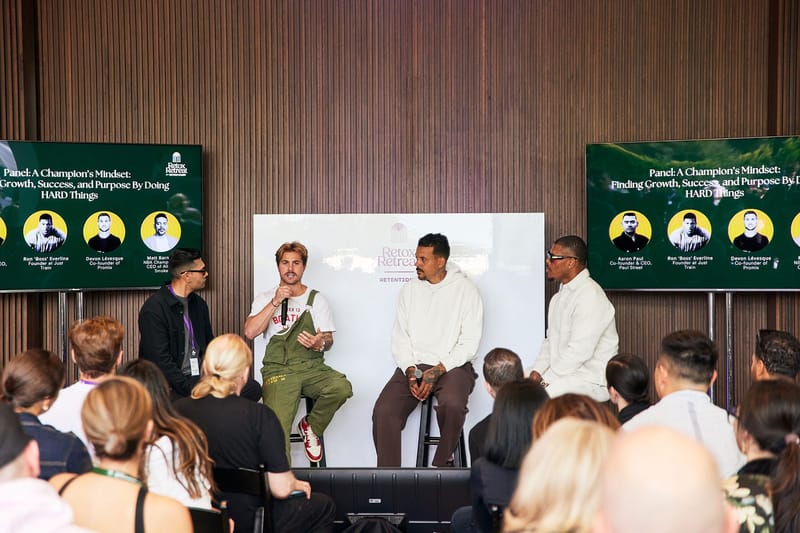 Panel of speakers and a host in front of screens reading Panel: A Champion's Mindset