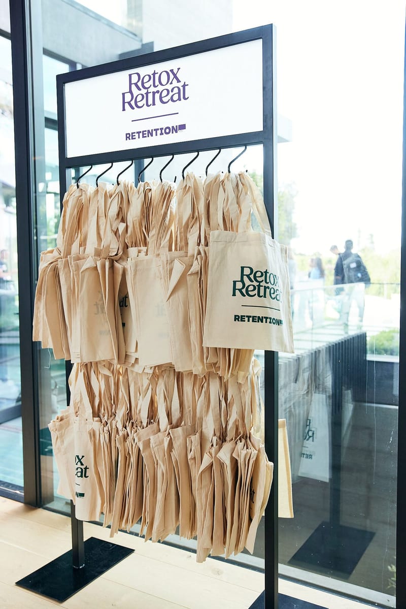 Rack of canvas tote bags hanging under a Retox Retreat and Retention sign