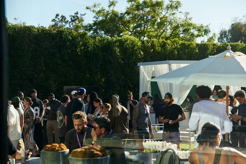 Guests crowding around an outdoor food table under white umbrellas and a canopy