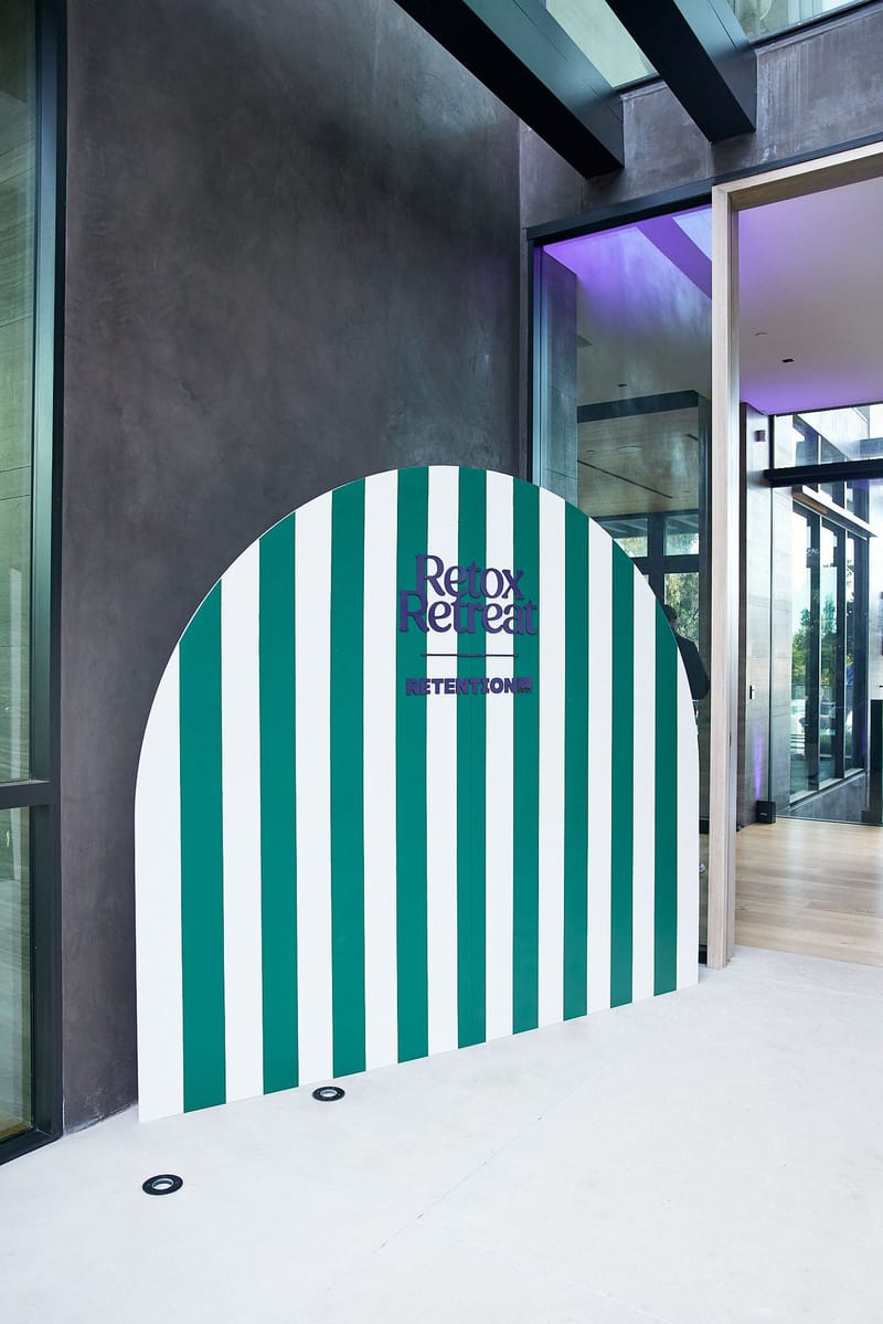 Green and white striped arched panel with the Retox Retreat logo beside a glass entrance