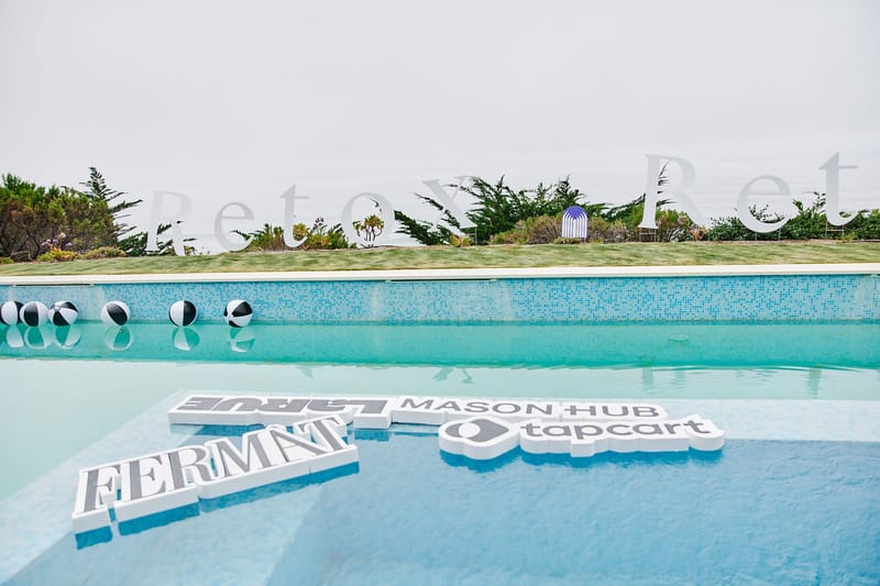 Foam FERMÀT, MASON HUB and tapcart logos floating in the pool below white Retox Retreat letters