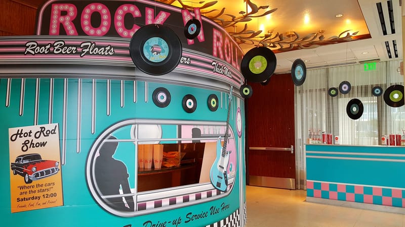 Teal diner front with Rock N Roll marquee lettering, Root Beer Floats and Thick Malts signs and hanging vinyl records