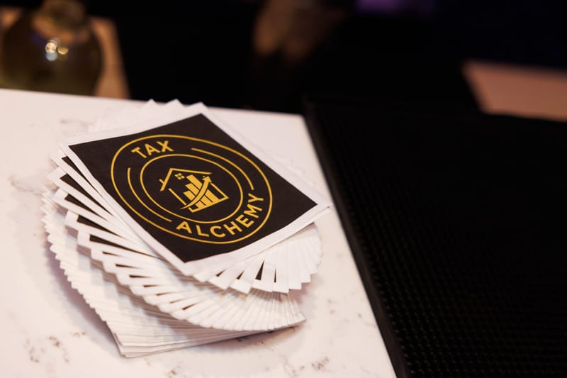 Stack of black cards printed with the gold Tax Alchemy logo on a marble counter