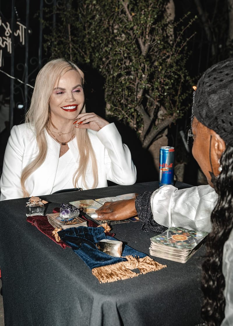 A smiling guest in a white blazer at a tarot reading table with cards and a velvet cloth