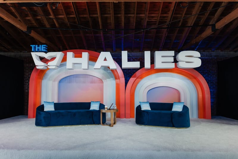 The Whalies stage with two orange and white arched frames, navy velvet sofas and large lettering
