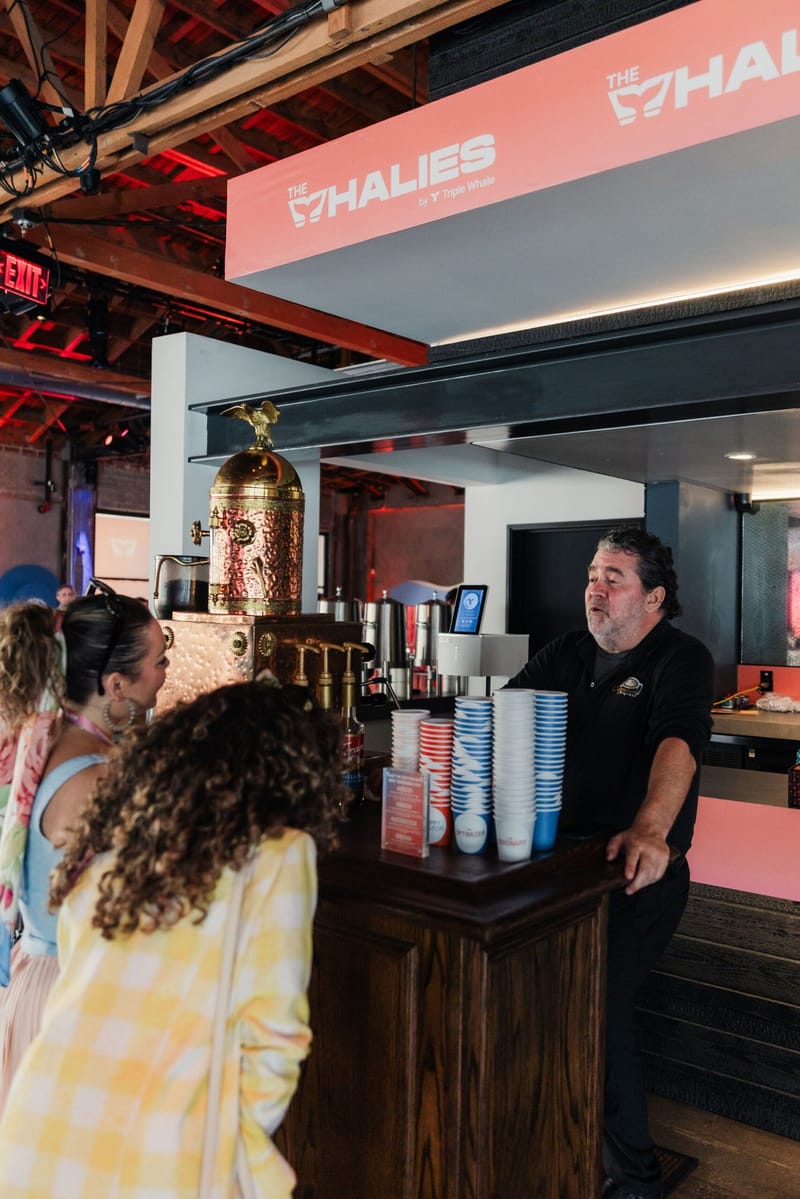Guests ordering at a coffee bar under a coral The Whalies sign