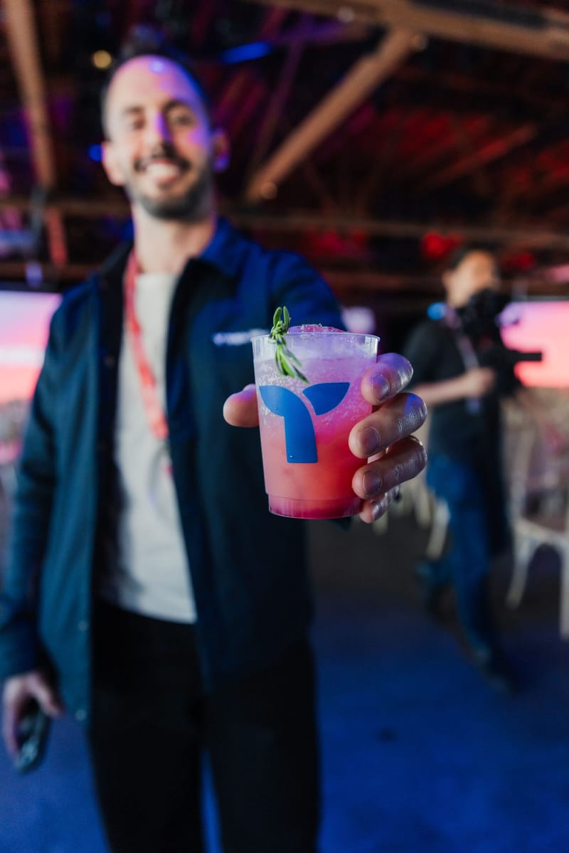 Guest holding a pink drink in a cup printed with the Triple Whale logo