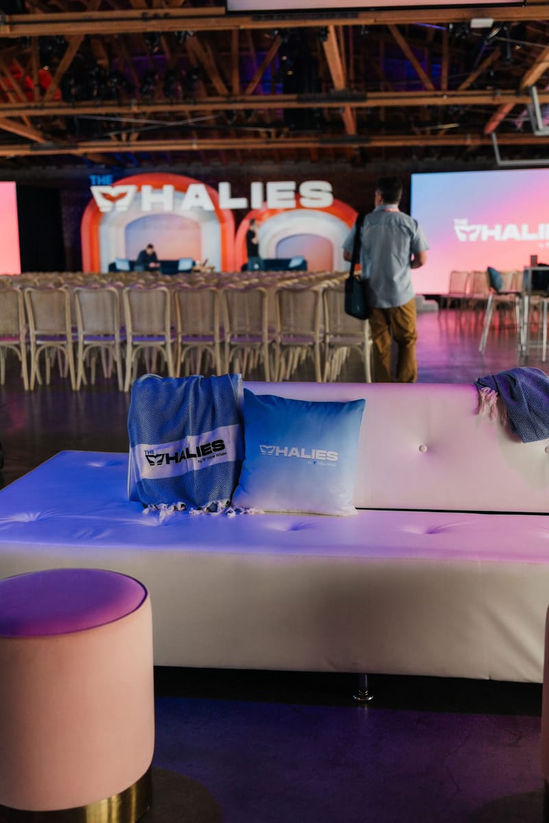 White lounge sofa with Whalies cushions and blankets facing rows of chairs and the stage