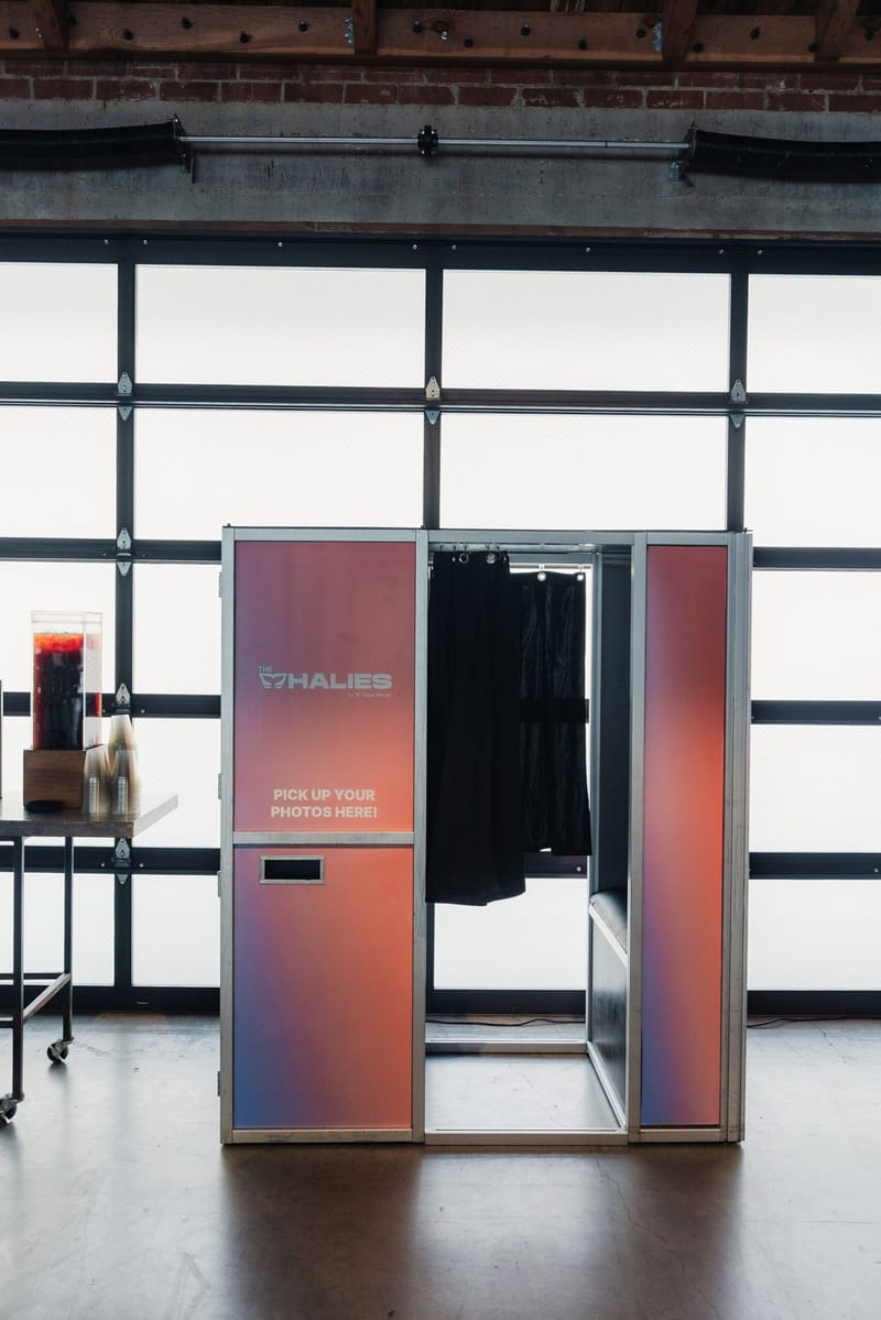 Whalies photo booth with a curtain and a sign reading Pick up your photos here!