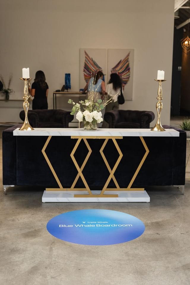 Gold geometric console with white flowers and candlesticks behind a Blue Whale Boardroom floor decal