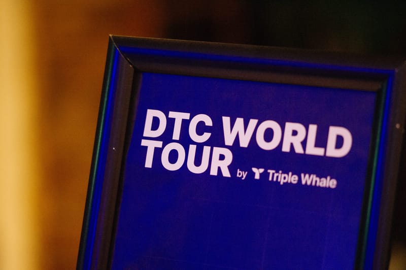 Framed sign reading DTC World Tour by Triple Whale in blue light