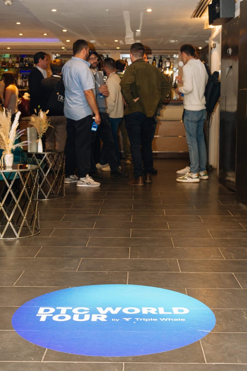 Guests gathered at a bar counter with a DTC World Tour floor decal in the foreground