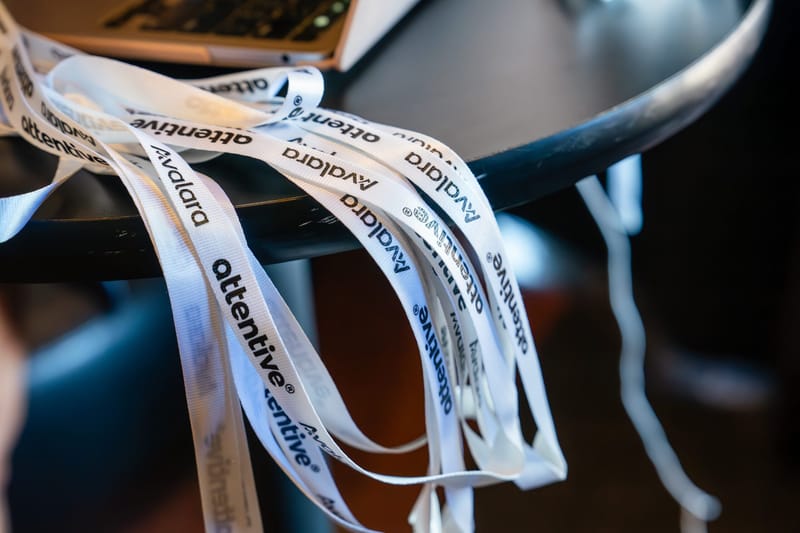 White lanyards printed with the attentive and Avalara logos draped over the edge of a black table