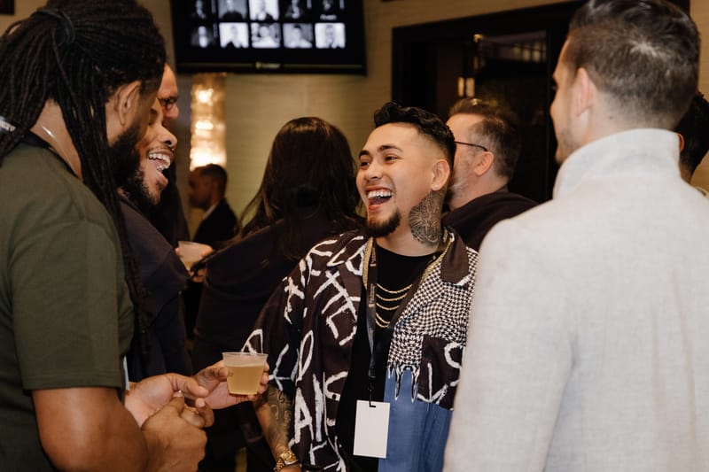 Guests in lanyards laughing together with drinks in hand