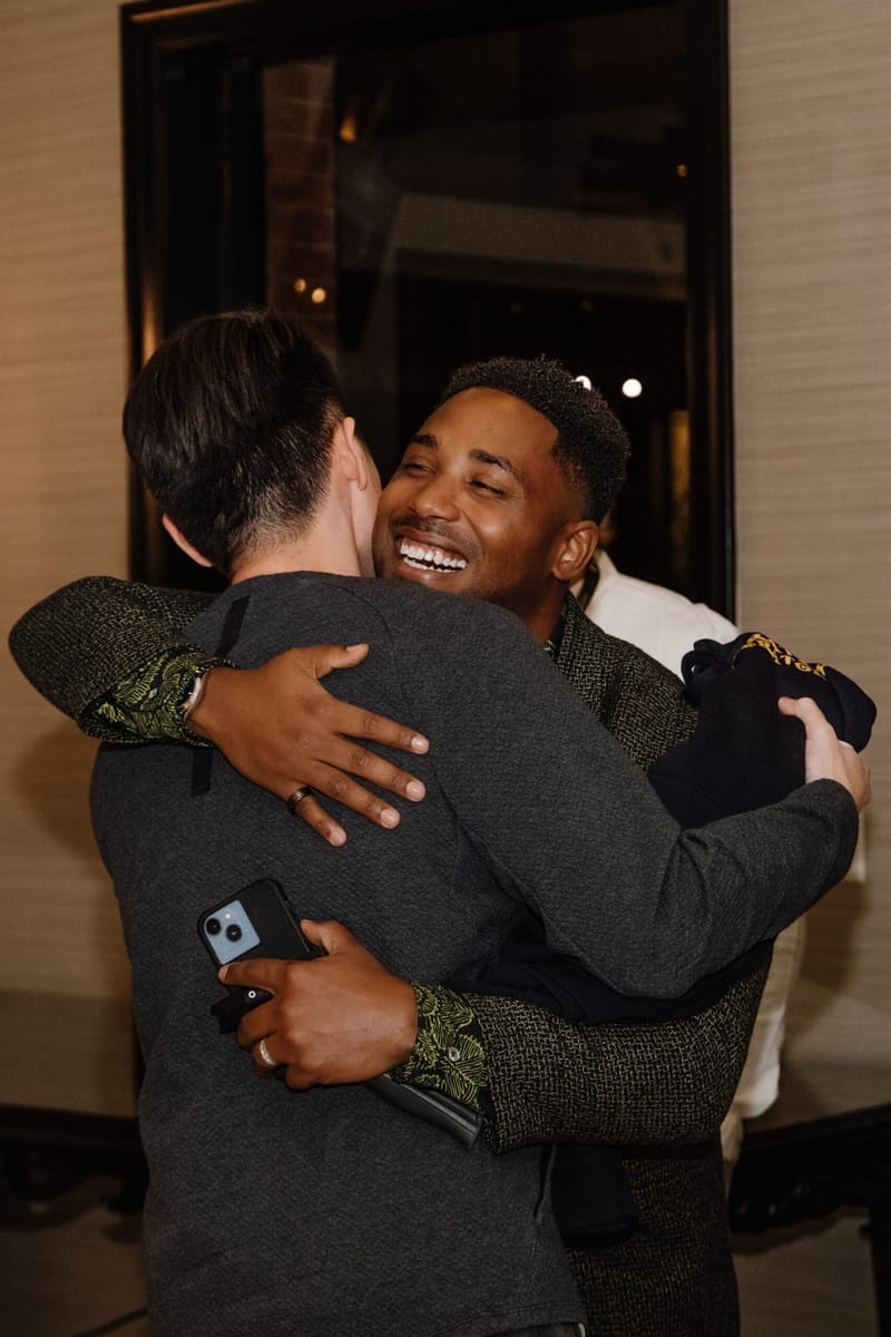 Two guests sharing a hug in a doorway at TSA Live