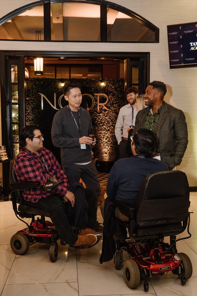 Guests talking in front of a greenery wall with NOOR lettering