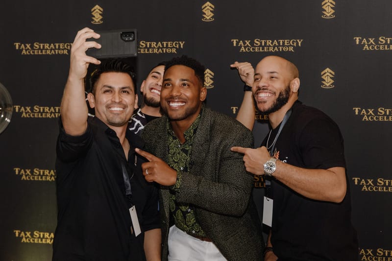 Four guests taking a selfie in front of a Tax Strategy Accelerator logo backdrop
