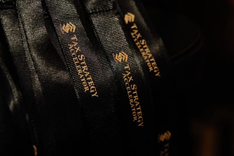 Black lanyards printed with the gold Tax Strategy Accelerator logo