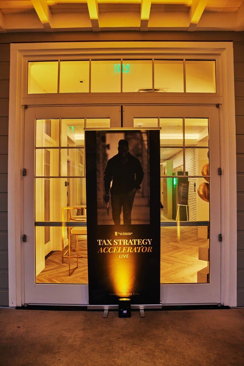 Tax Strategy Accelerator Live banner lit from below in front of glass French doors at night