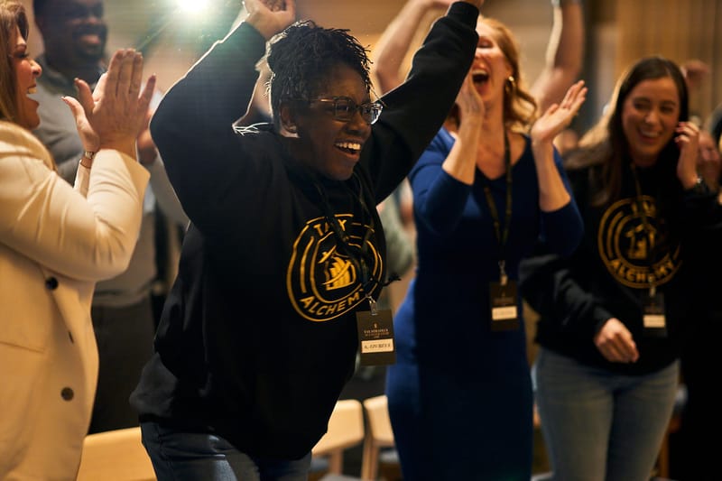 Cheering guests wearing Tax Alchemy sweatshirts and Tax Strategy Accelerator Live lanyards