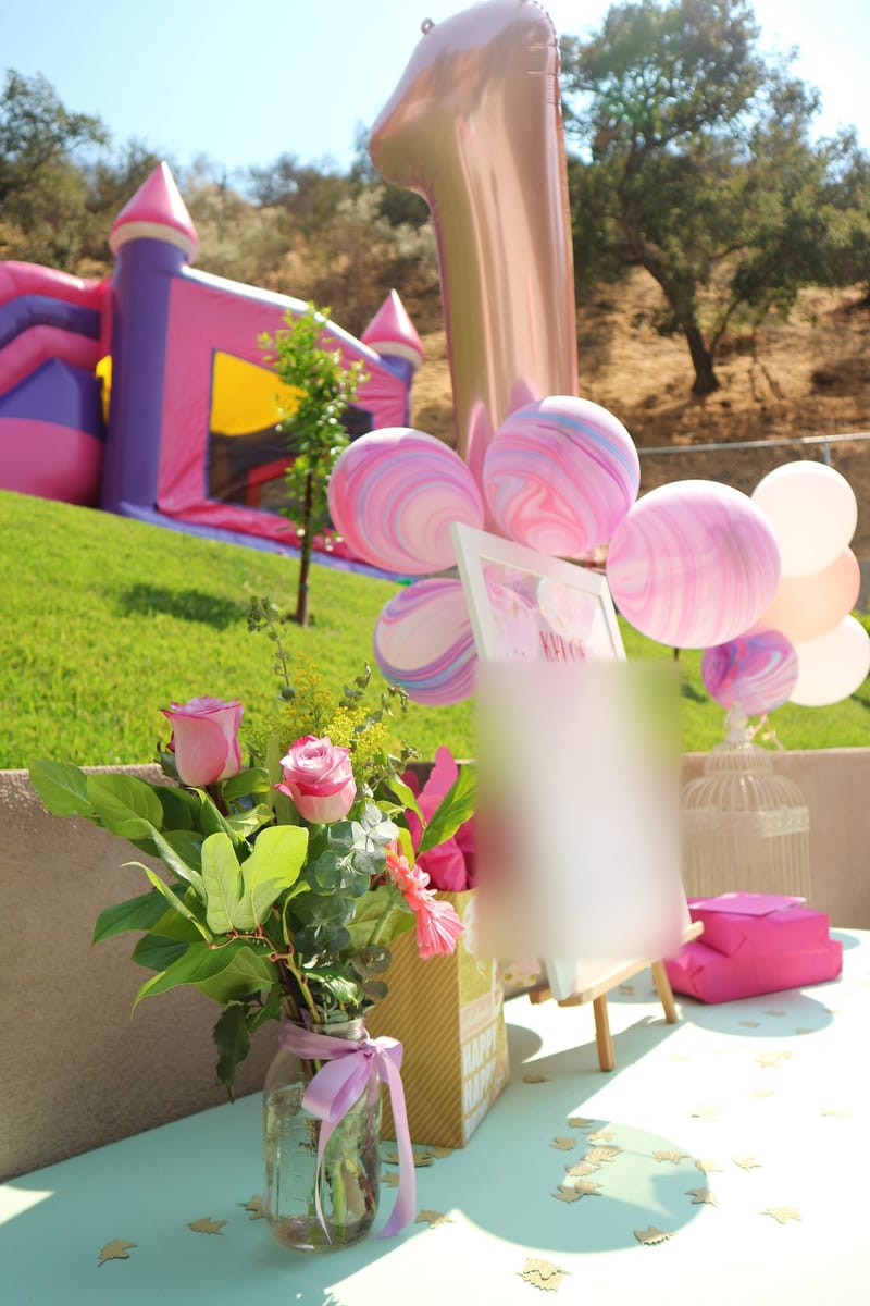 Birthday board on an easel with roses, marbled balloons and a rose gold number 1 balloon