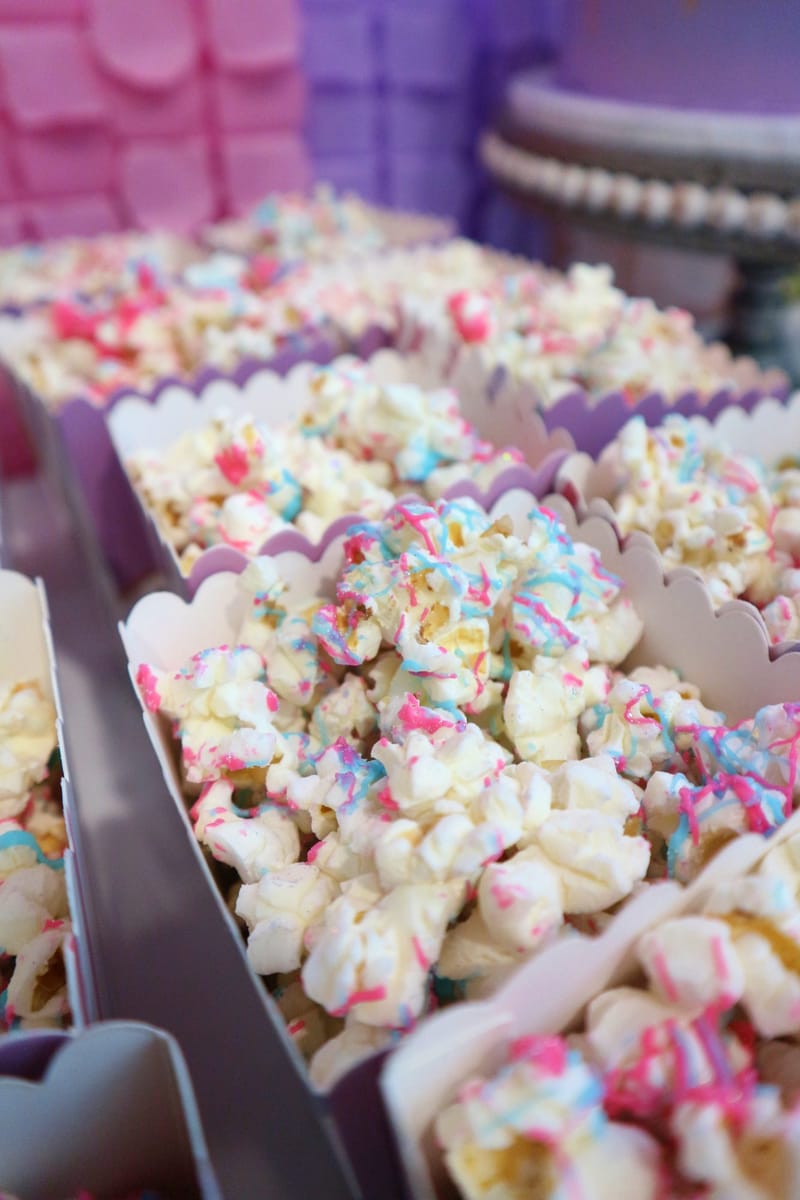 Unicorn popcorn boxes filled with popcorn drizzled in pink and blue