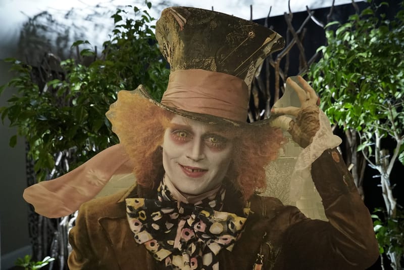 Mad Hatter cutout in a tall hat and polka dot bow tie among green trees
