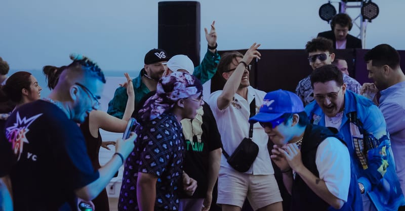 Guests dancing outdoors in front of a DJ booth and speakers under a grey sky