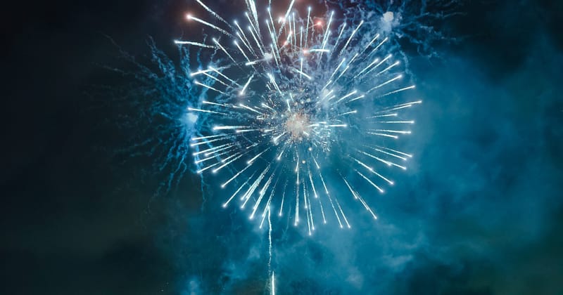 Blue firework bursting in a round spray above drifting smoke