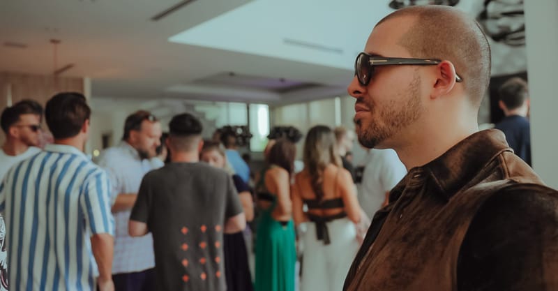 Guests mingling in a bright open-plan room, one man in sunglasses in the foreground
